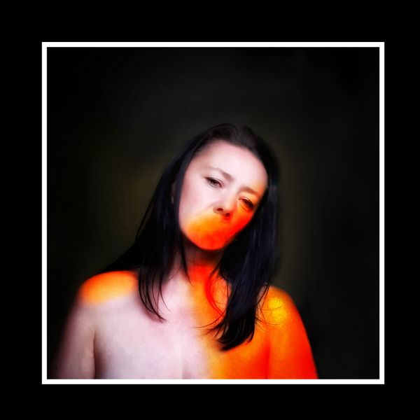 Silenced Ember. A band of orange light falls across the mouth and shoulder, the rest left in shadow.