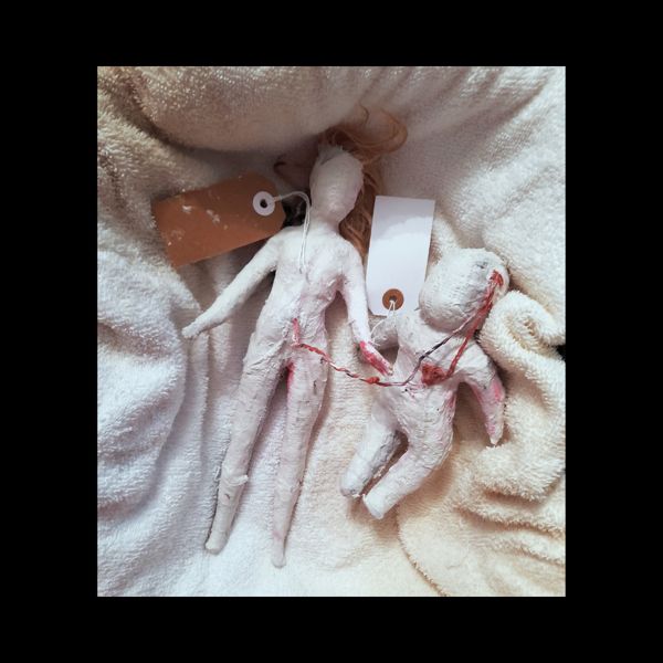 Tagged and Labelled. Two small white figures, one larger and one smaller, lie side by side on soft towelling.
